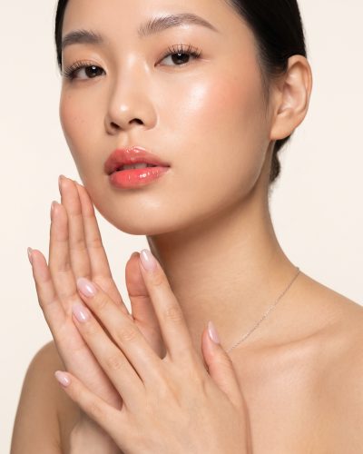 A hand resting near the jaw with a natural Builder Gel manicure.